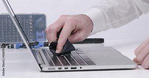 Service worker cleaning laptop keyboard buttons with microfibre cloth in white walled lab in 4k