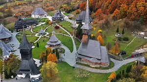 Aerial drone view of the Barsana Monastery, Romania. Main church and other buildings, visitors, hills covered with yellowing forest around
