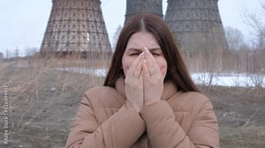 Puffs of dark smoke dirty clouds of toxic vapor are emitted from pipes. Epic factory production. Environmental problem pollution. A woman stands at the pipe and coughs.