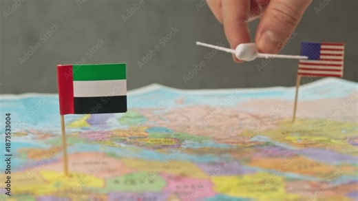 Toy airplane flying from United States to United Arab Emirates above colorful world map, symbol business conferences, luxury vacations, stopover tourism and premium air travel.