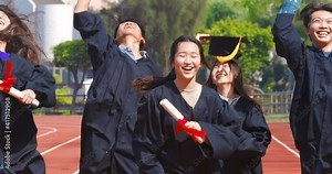 happy graduation students holding diploma and running on the stadium at school