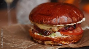 Tasty big fresh hamburger with grilled beef meat,vegetables & sauce served on rustic paper in meat restaurant.Fast food cafe menu item.Roasted cutlet in fresh crusty bun