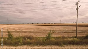 Traveling by Train Through the Countryside. Passenger point of view as a train moves through the rural countryside. Views of farm land and corn crops.