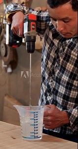 Carpenter mixing epoxy resin with an electric mixer