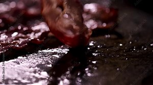 Closeup shots of sizzling bacon cooking on a grill with crispy and juicy textures