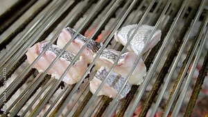 Close-up of fish fillets grilling over hot coals, highlighting the cooking process and fresh seafood. Emphasizes the heat, texture of the fish, and the art of barbecuing seafood to perfection.