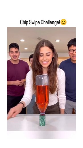 LaughingLlama on Instagram: "Chip Swipe Challenge! This X post from @LivingTricks_ (posted today, Nov 26, 2025) features a hilarious 19-second video of the "Chip Swipe Challenge." A group of young friends (mostly guys, one woman) gathers around a table in what looks like a home kitchen. The setup: a plastic bottle filled with red liquid (like soda) topped with a stack of green poker chips. They use a wooden stick (like a ruler) to swipe underneath—aiming to knock off the chips without toppling t