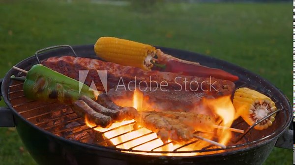 CLOSE UP: Eruption of a large fire flame while grilling vegetables and seasoned meat for a delicious meal at a summer BBQ garden party. Towering flames rising up through the grilling cooking grate.