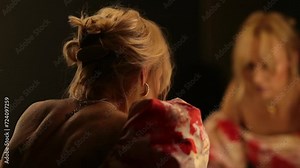 Sad woman in front of a mirror in a dark dressing room.