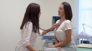 Female doctor listening the heart beat of a patient with the stethoscope, checking the health