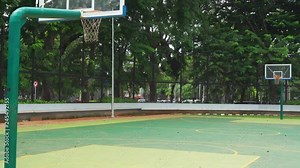 Outdoor basketball court with two basket hoop and green trees background at the park. Shot in 4k resolution