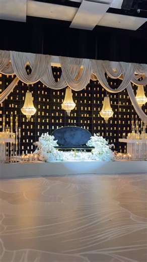 Diya Decor on Instagram: "Dramatic Crystal Affair ✨ Where bold drama meets timeless elegance. Champagne drapery frames a shimmering crystal wall and glowing candle backdrop that instantly captivates. Twin 8-ft white tables overflow with cascading florals, flanked by 10-arm candelabras and soft candlelight. Guest tables glisten with crystal accents, while family tables shine with mirror tops and 25-arm gold candelabras the epitome of luxury and charm. 💌 Email us: info@diyadecor.com [reception se