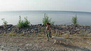 Young woman running with her dog near a coast - Free Stock Video