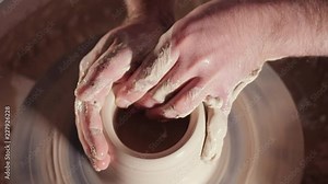 Traditional pottery making, man teacher shows the basics of pottery in art studio. Artist operates hands, which gently creating correctly shaped handmade from clay