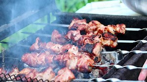 Grilled meat on the grill with open fire. Shashlik, traditional Georgian food. Woman’s hand puts meat skewer on brazier. Roasted meat video, BBQ party outdoors in the backyard, summer activities