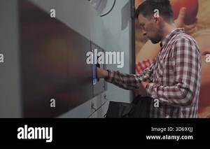 Man returns plastic bottles at reverse vending machine in German supermarket. This eco-friendly process promotes recycling, waste reduction, and environmental sustainability through deposit refunds.