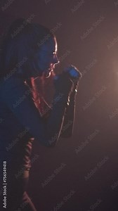 Beautiful strong woman kickboxer alone is engaged in a dark sports hall, beats a punching bag, in slow motion. Aggressive sports woman training endurance strong workout.