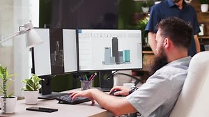 In creative media house two professional architects are using 3D software to design new buildings. In the background - cozy and modern styled office