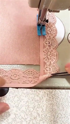 Sewing a delicate pink lace trim onto a soft pink fabric piece using a metal sewing machine tool