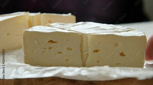 Cutting sectors of soft cheese brie or camembert, close up