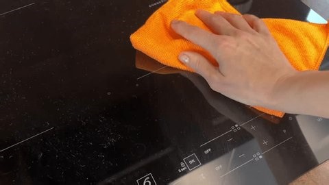 clip-3988909531-close-up-video-hand-wiping-induction-cooktop-orange