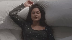 Exhausted woman lays back on pillows in bed