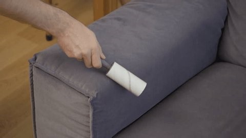 clip-3989591689-person-uses-sticky-lint-roller-remove-dust