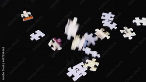 Slow motion of randomly falling pieces of the puzzle filling the black background. Close-up