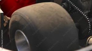 Close-up of the motor, transmission and smooth tire of the go-kart, transmission chain and gears are visible.