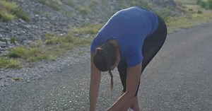 Female athlete doing stretching exercises in nature. Woman runner stretching body muscles