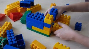 Child play with colored plastic bricks. Construction of toy building - educational game. Stock Video
