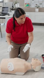 CPR, defibrillator and dummy with woman on floor for rescue or resuscitation course and demonstration. Emergency, first aid and paddle presentation with instructor in office for medical education
