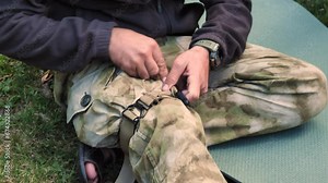 The tactical medic applies the tourniquet to his leg. A military instructor demonstrates applying a tourniquet to stop bleeding on a leg. Military Medicine