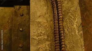 Close-up of an industrial rotary switch with thick electrical cables mounted on a rough concrete wall, showcasing vintage electrical equipment and manual controls.