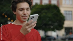 Attractive Man Making Voice Message or Using Virtual Assistant App on Mobile Phone. Young Guy Recording Voice Message on Speakerphone While Walking on the Street. Technology Concept