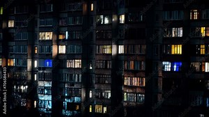 Night time-lapse in the windows of a multi-story building. Life in a big city. Serenade of Light. Time-lapse footage of residential apartment windows that light up and turn off at night.
