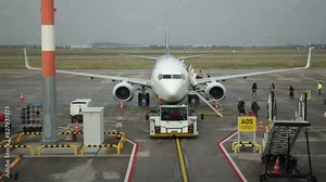 Aircraft boarding passengers, Ground operations, Boarding process. Ground support staff and equipment surround airplane on tarmac as passengers board via mobile staircase.