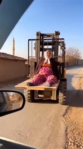 hayalet on Instagram: "Ahsap bir palet üzerinde oturan kilolu, yaslica bir Turk kadinini tasiyor. Kadin, üzerinde parlak pembe cicekli genis bir salvar, koyu renkli bir hirka ve beyaz bir basörtüsü ile tipik bir köy kadini figürü. Forkliftin çatallari yaklasik bir metre yüksekte. Araç hizla yanindan geçerken, forklift aniden one dogru devrilmeye basliyor, arka tekerlekleri havaya kalkiyor ve on çatallar hizla asfalta dogru çakiliyor. Kadinin saskinlik ve korku dolu ifadesi net bir sekilde seçili