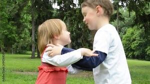 children (siblings - boy and girl) give a kiss in park