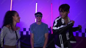 Diverse street dancer moving to city pop music at party with neon light while man wearing fancy glasses. Attractive hipster perform or practicing dancing together while looking at camera. Regalement.