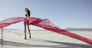 Girl with a fabric walking and dancing in the desert