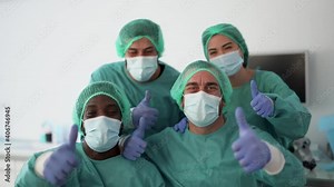 Doctors and nurse with thumbs up while wearing surgical face masks for coronavirus outbreak - Health care worker inside hospital wearing hazmat suit
