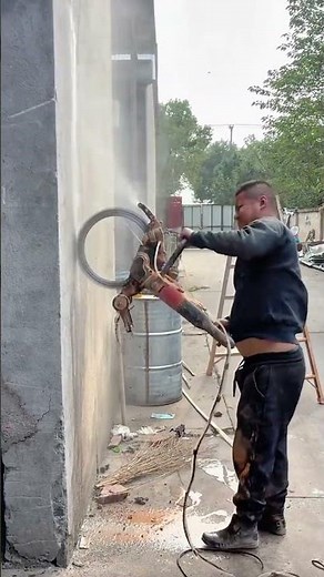 Worker cutting concrete wall using high-pressure circular saw