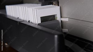 Slide magazine projector in operation. Closeup of antique white slider projector working to project slide photographs and to create slideshow. Thin-film slides in a white plastic frame. Vintage produc
