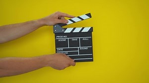 clip-1077227957-hands-using-film-clapper-board-close-up