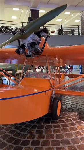 Exploring a Vintage Orange Biplane in a Museum