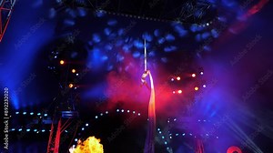 A slender aerial gymnast performs on a suspended fabric in the circus arena, she performs complex tricks.The acrobat falls upside down on the fabric under the dome of the circus in red light and smoke