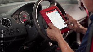 Auto electrician uses OBD2 scanner and tablet to diagnose vehicle faults. Professional mechanic checks car diagnostics, performs auto repair service, ensures vehicle maintenance, upgrades software.