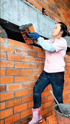 Careful bricklayer positioning clay blocks to build a sturdy wall above a concrete beam