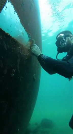 Guy removes barnacles from old boat